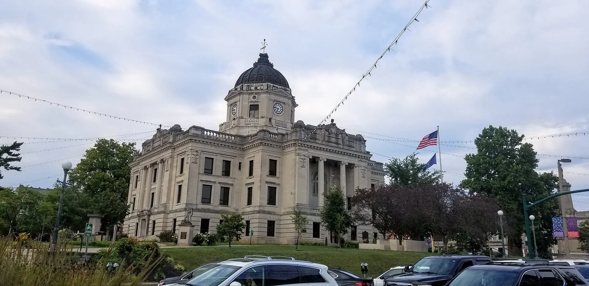 The Monroe County Courthouse, a domed limestone building, behind a row of parked cars and string lights